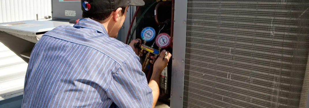 HVAC technician servicing a condenser unit in Hamilton